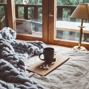 A cozy bed with a cup of tea in a cabin Airbnb rental in the Poconos.