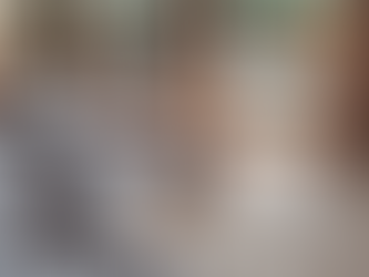 A cozy bed with a knit blanket in front of a glass door that leads to a deck.