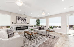 A bright modern room that has been staged with neutral furniture and accent pieces.