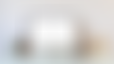 Desktop computer on a minimalist desk displaying the ChatGPT home screen, with books, a small plant, pencils, framed art, and a coffee cup.