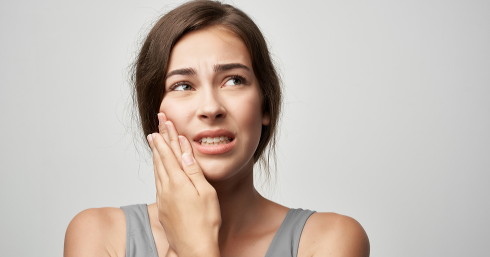 Young woman holding her jaw in discomfort, illustrating TMJ pain and jaw tension that masseter Botox at Carolina Aesthetic Collective in Raleigh, NC can help relieve.
