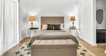 A bed with two side tables and lamps in a one bedroom apartment.