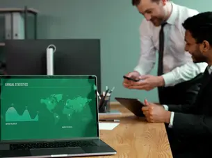 A modern business professional looking at marketing analytics on a laptop, with graphs and charts displayed on the screen