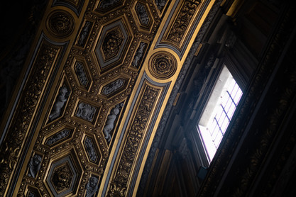 Elaborately carved and gilded coffered ceiling inside a historic Roman church.