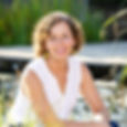 Portraitfoto von Andrea Schmallegger. Sie sitzt an einem Teich im Hintergrund sieht man einen Steg