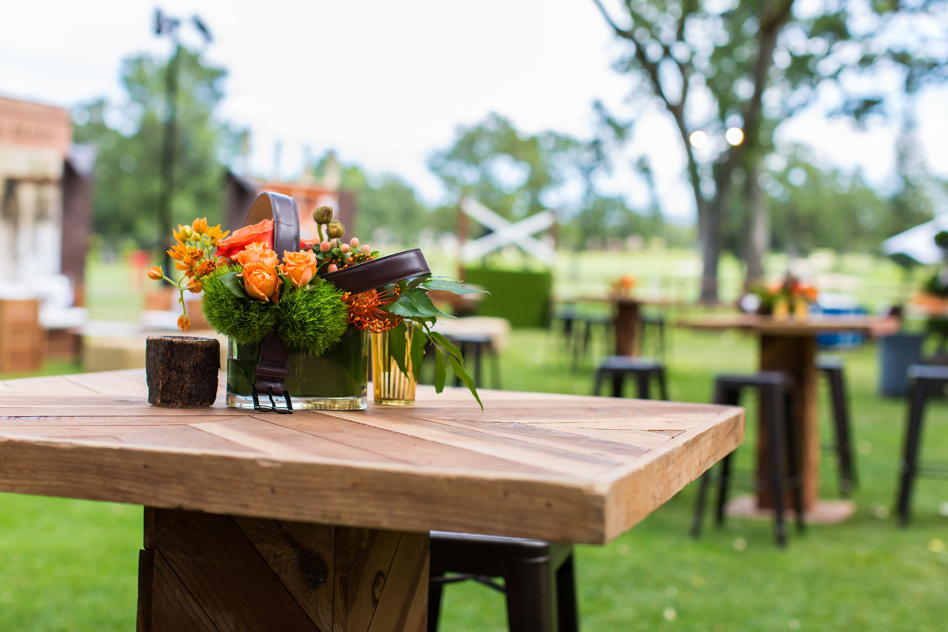 close-up of rustic event table with orange floral arrangement and equestrian decor centerpiece