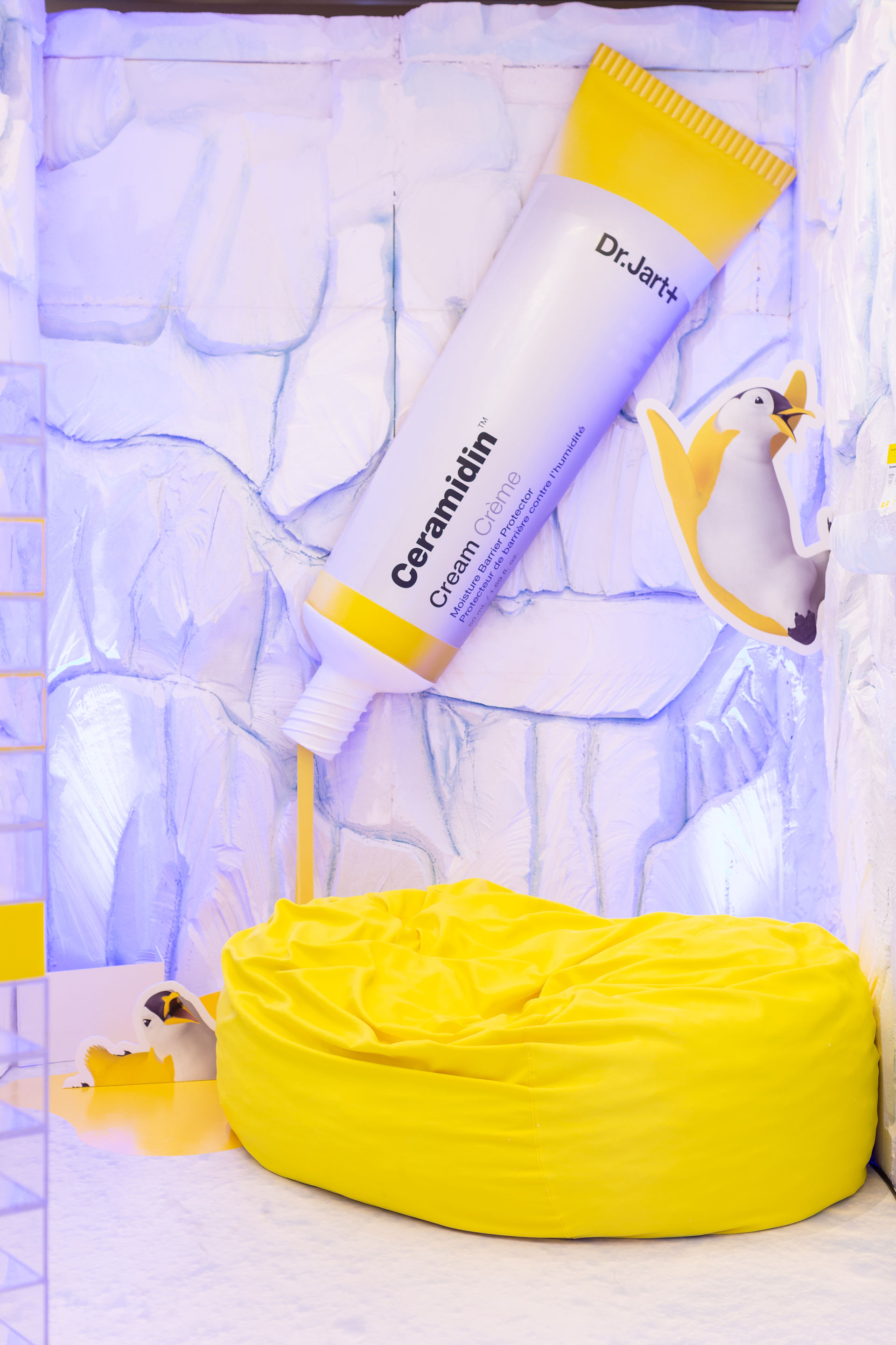 Oversized Ceramidin Cream tube pouring into bean bag in winter-themed display