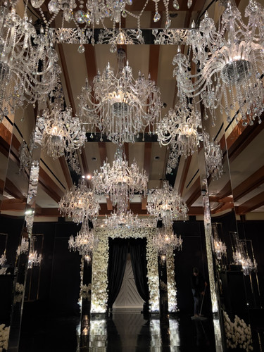 Close-up of mirrored wedding decor with crystal chandeliers and floral arch