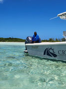 man sitting in the crystal bay boat as it floats by a beutiful exuma island