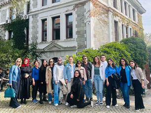 Ivy kaplı tarihi binanın önünde gülümseyen 13 kişilik grup, taş döşeli avluda poz veriyor. Boğaziçi Üniversitesi, P4C Eğitmen Eğitimi