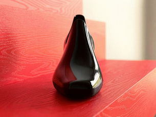 Sculptural ankle boot made of shiny black plastic material with an elongated toe and an oblique geometric heel.