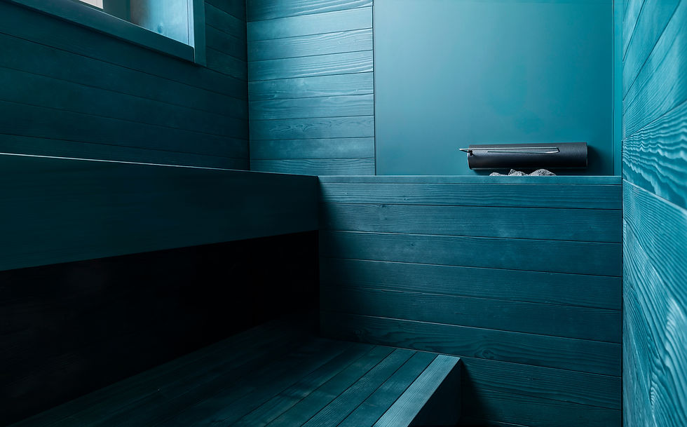 An interior photography focusing on a modern teal-colored wooden sauna by Starpool at Tyrol Hotel in Selva di Val Gardena, showcasing a close-up of the sleek geometric wood panels, benches, and stone heater, photo direction and production Laura Pozzi Studio.