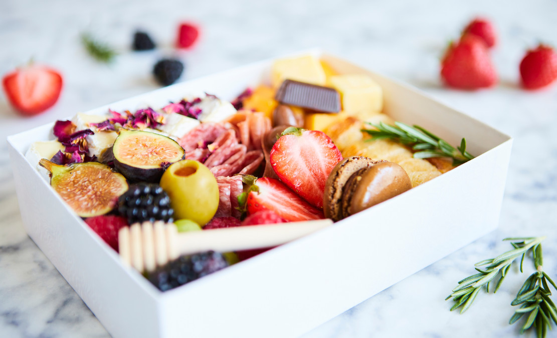 Grazing box by Suikerbekkie in Heist-op-den-Berg, featuring an assortment of fruits, cold meats and cheeses in a white box for a stylish sharing platter.