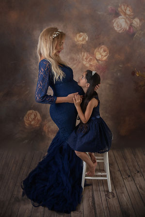 a pregnant lady in a navy coloured tulle dress with her daughter in a matching dress at her maternity photoshoot in hampshire