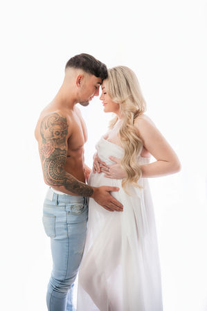 a pregnant woman and her partner standing face-to-face, the partner holding his pregnant wife's bump