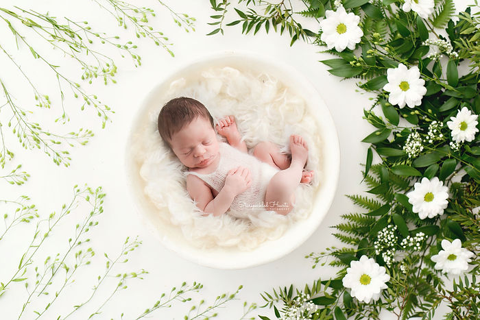 gorgeous newborn baby girl lying in a large white bowl fast asleep for her newborn photography session