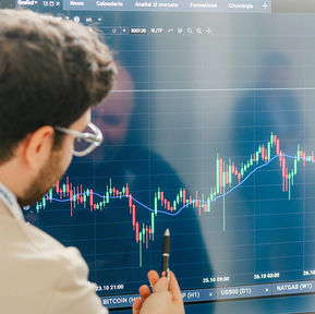 Uomo con occhiali analizza grafico finanziario su grande schermo.
