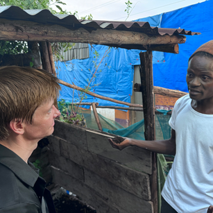 Two men conversing near a shack; Speakers for Africa Nonprofit promoting sustainability in Uganda.