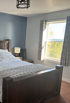 Modern bedroom with dark wood bed frame and blue accent wall with view of ocean through window