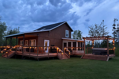 Wooden cabin with string lights on the deck at dusk
