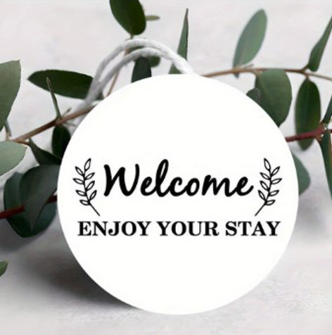 Round welcome tag with text Enjoy Your Stay and eucalyptus.