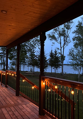 String lights on a wooden porch overlooking Sturgeon Bay, PEI at dusk.