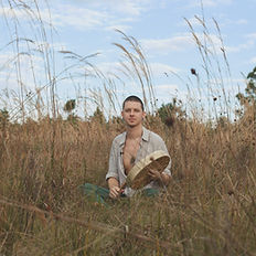 Dakota Dawkins sitting in nature playing sacred sounds during an Ancestral Healing Activation