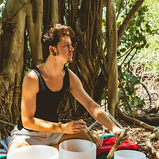 Dakota Dawkins sitting in nature playing sacred sounds during an Ancestral Healing Activation