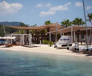 La Guérite’s beachfront setting at D Maris Bay, with turquoise water, white cabanas and palm trees in Muğla.