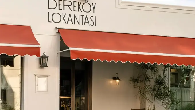 The white entrance façade and red awnings of Dereköy Lokantası in Bodrum, Muğla.