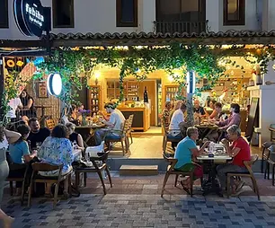Guests dining outside the warmly lit Febiha 1921 restaurant in Akyaka, Muğla, during the evening.