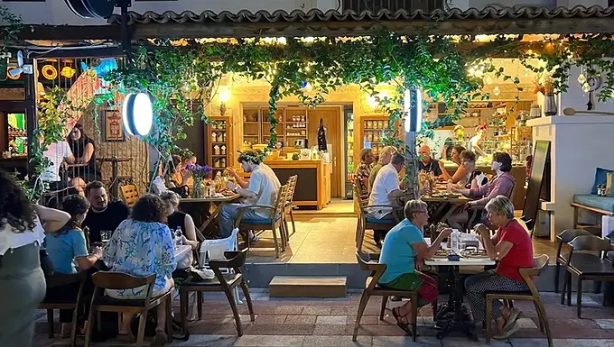 Guests dining outside the warmly lit Febiha 1921 restaurant in Akyaka, Muğla, during the evening.