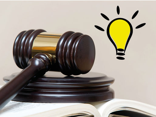 Richterhammer liegt auf einem Buch, darüber schwebt eine erleuchtete Glühbirne