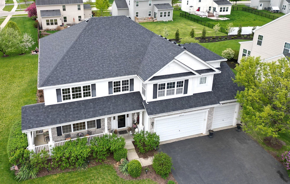 Large white two-story house with dark roof, green lawn, suburban neighborhood.