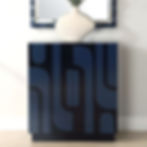 Navy blue cabinet with abstract design under a white vase and mirror.