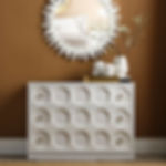 White dresser with circular design, sunburst mirror in the background, elegant decor.
