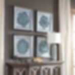 Four framed peaceful hand-painted canvas above a console table