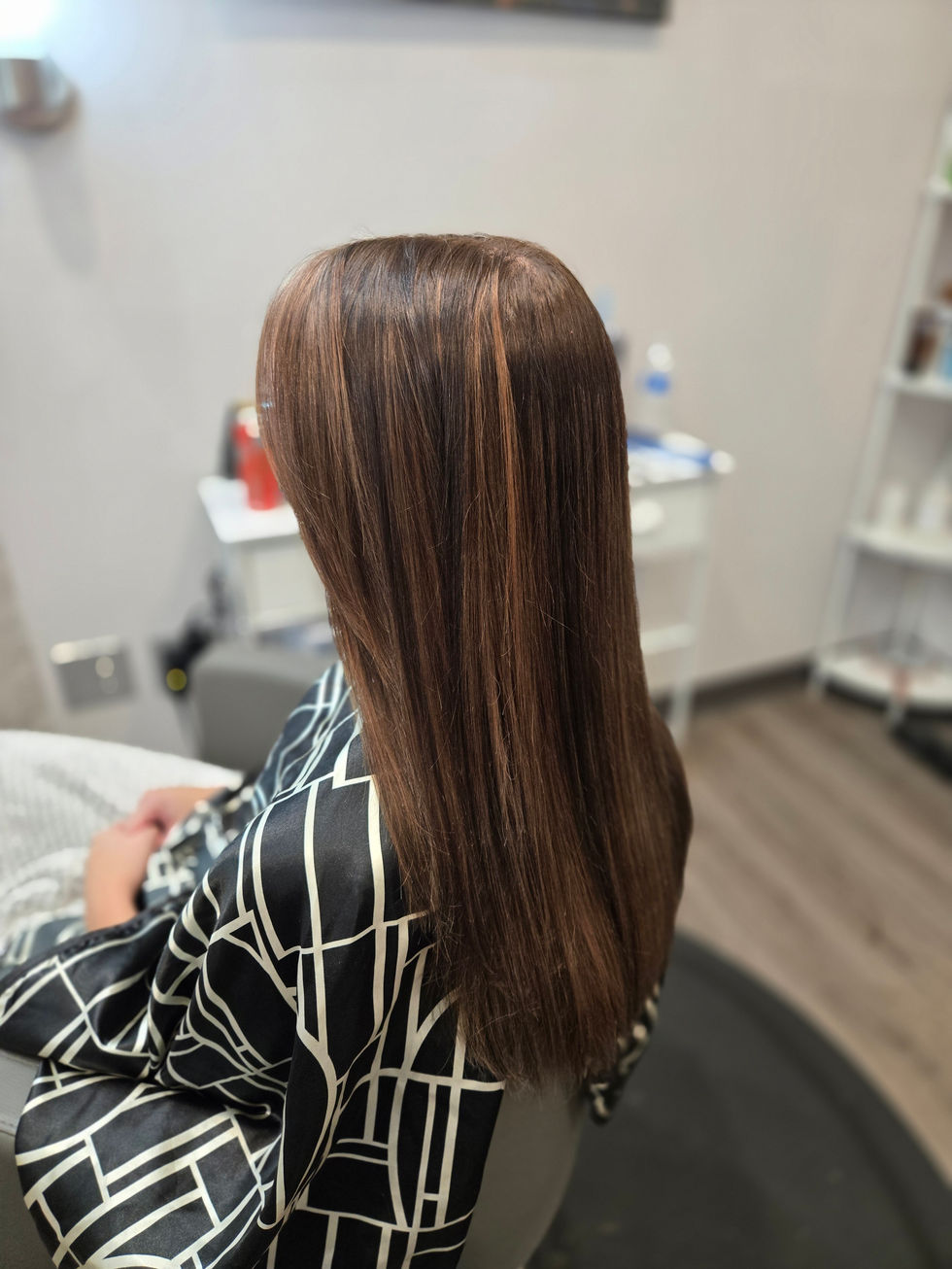 Person with long, straight brown hair in salon.