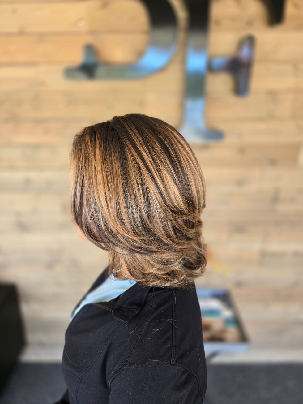 Woman with styled, highlighted hair in a salon.