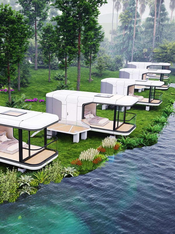 Small modern houses white cabins with decks line a lush green riverbank, surrounded by trees and plants, exuding tranquility in a natural setting.