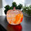 Thumbnail: Clear glass pumpkin jar with a orange and white swirl, displayed on a tabletop with greenery in the background.