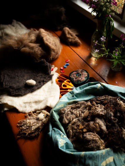 Lampaanvillaa, saksia ja muita kehruukurssin tarvikkeita tuvan puisella pöydällä