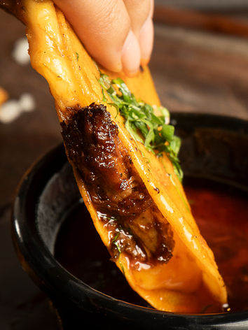 3 tortillas de maíz con birria de brisket, mix de quesos, cebolla, caldo de birria y cilantro.