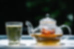 A glass tea kettle brewing herbal tea vs green tea in a glass