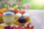 Tea in a yellow ceramic mug next to a plate of cupcakes