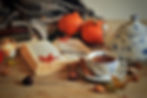 Maple tea on a table with a book, eyeglasses, candles, a pumpkin, and maple leafs