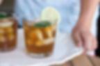 A woman serving a tray with two glasses of iced tea