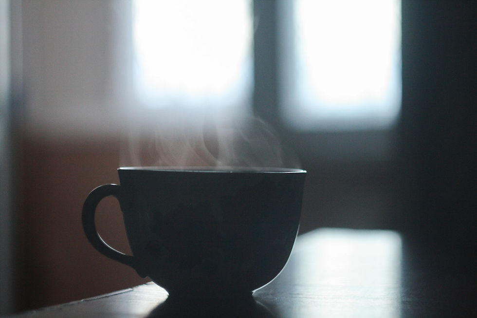 A cup of steaming oolong tea sitting on a desk in the morning