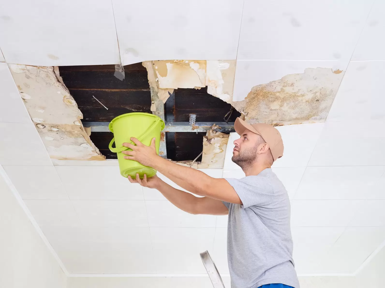 Man-Catching-Water-from-Ceiling-Leak.webp