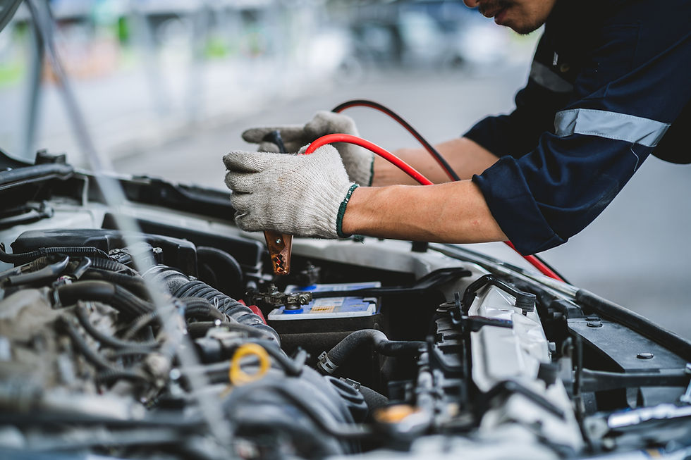 Asian technician measures car battery voltage at service station Maintenance and repair. T